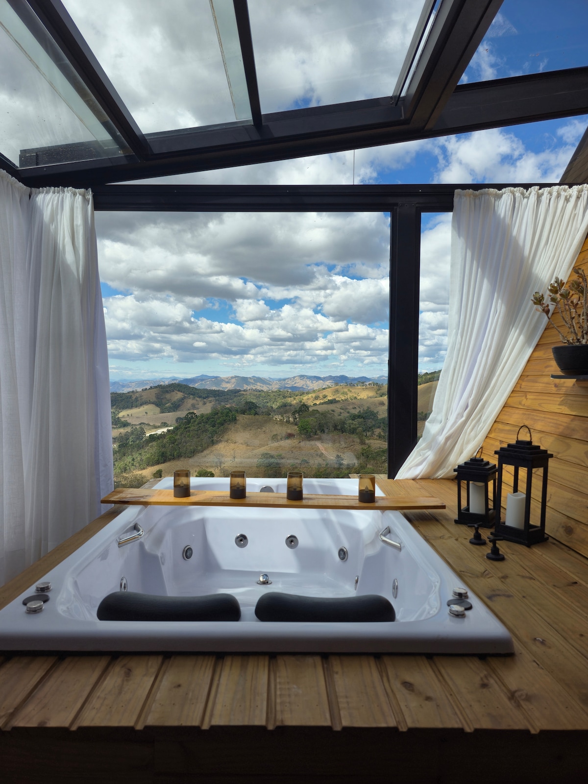 Hidromassagem dupla com o teto de vidro aberto e vista para as montanhas