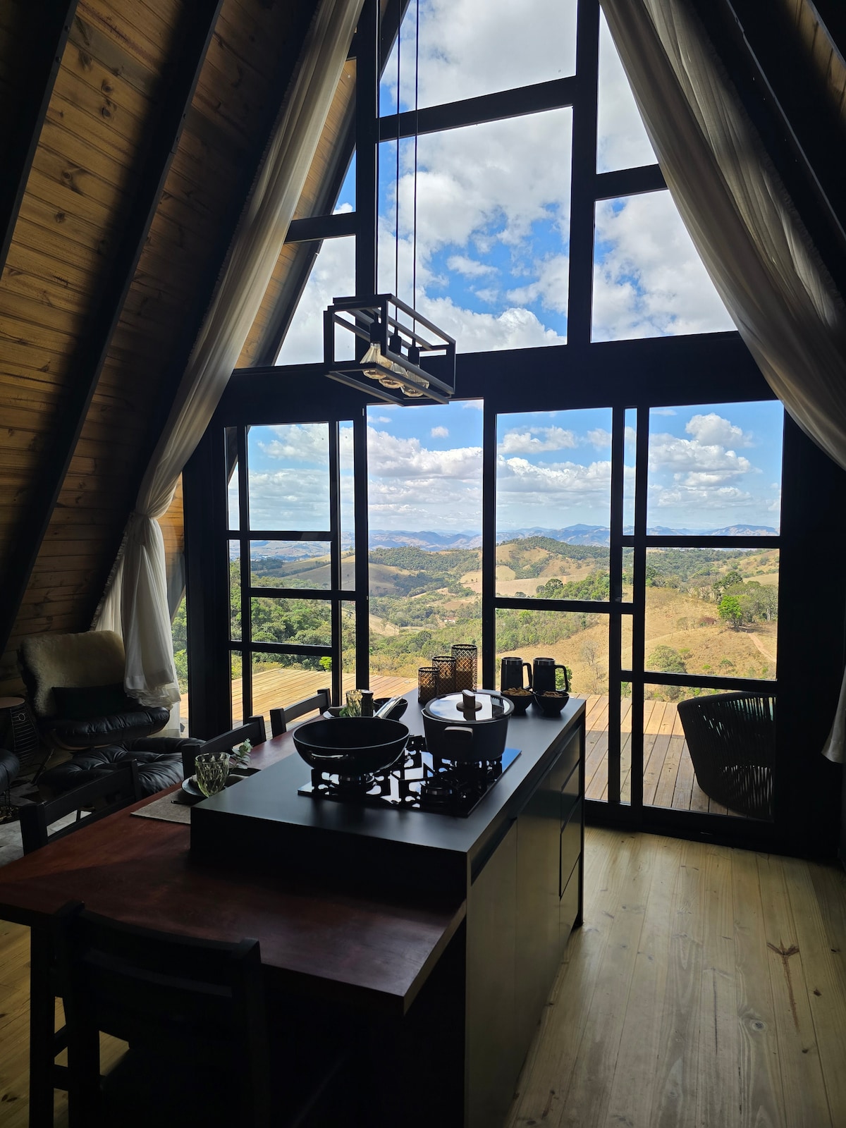 Cozinha e sala com janelas de vidro do chão ao teto e vista para a serra